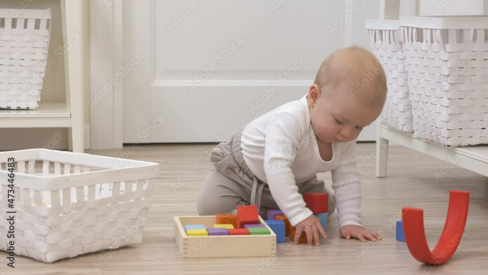Baby boy sitting on the floor playing with colorful wooden building blocks and rainbow stacker, 9 month old kid picks up cubes at home. High quality 4k footage Baby boy sitting on the floor playing with colorful wooden building blocks and rainbow stacker, 9 month old kid picks up cubes at home. High quality 4k footage