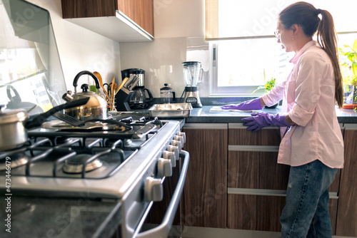 Young cute latin housewife cleaning housekeeping the kitchen.