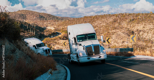 Overtaking trucks on a road curve in a rural landscape at sunset