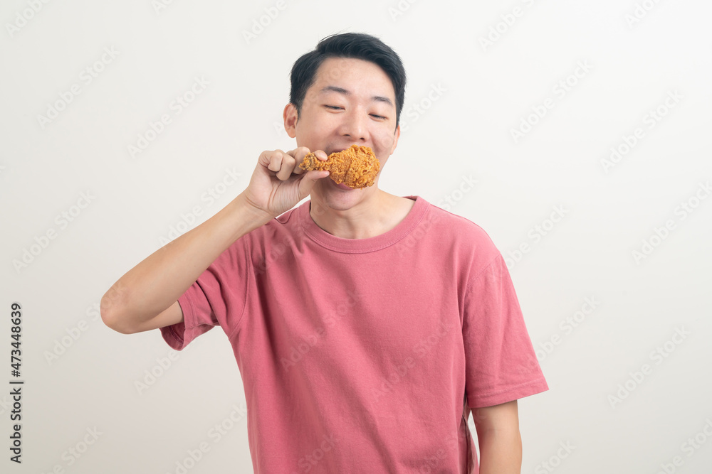 young Asian man with fried chicken on hand young Asian man with fried chicken on hand