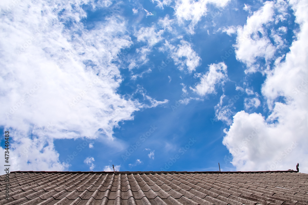 Clouds on bright blue sky and roof home on background Clouds on bright blue sky and roof home on background