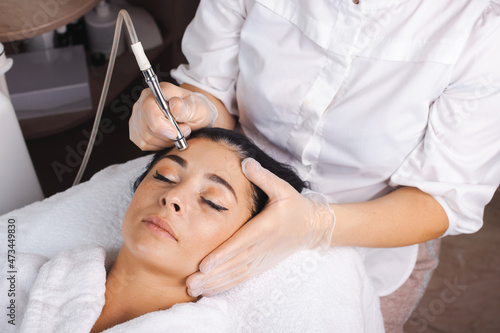 Close-up portrait of a caucasian woman getting facial hydro microdermabrasion peeling treatment in a spa salon photo