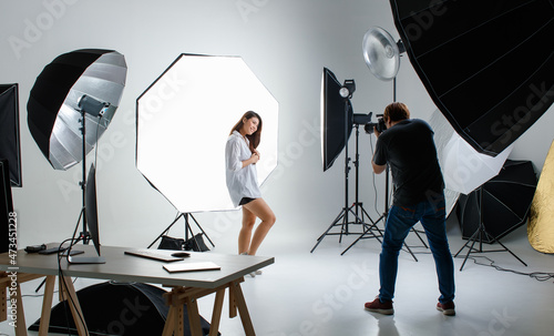 Photographer and pretty model working in modern lighting studio with many kinds of flash and accessories.