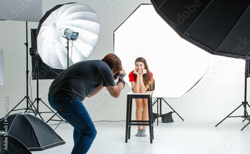 Photographer and pretty model working in modern lighting studio with many kinds of flash and accessories.