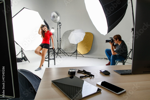 Photographer and pretty model working in modern lighting studio with many kinds of flash and accessories. photo