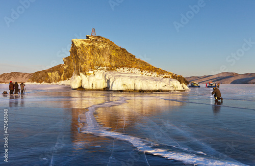 Frozen Baikal Lake at sunset in February. Beautiful rock of Kobylia Golova or Horse's Head is natural landmark and a place of attraction for tourists and photographers. Ice travels and photo tours photo