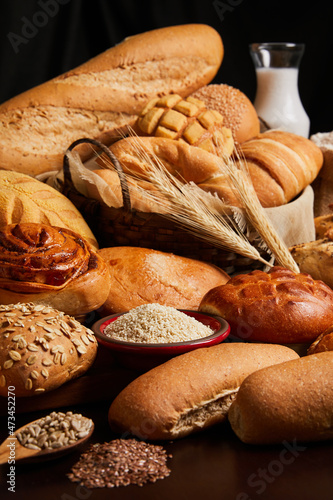 Close up of bread basket with milk, flour and ears of wheat on the table. Food and bakery concept. Vertical photo.
