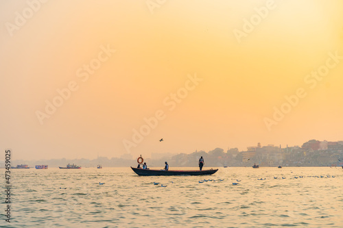A flock of seagulls flying around the tourist boats at Varanasi