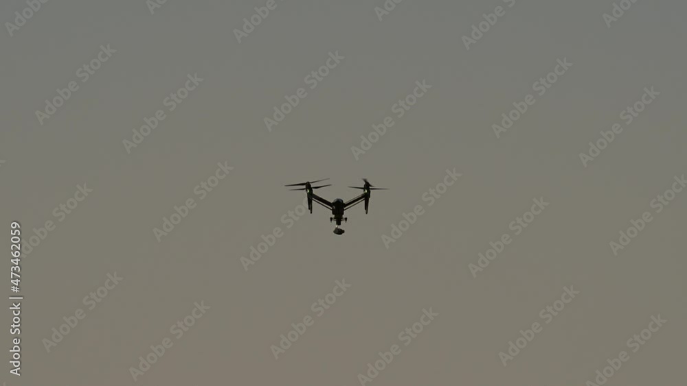 A drone hovers up in the sky on a bright sunny day, Drone hovering, Drone camera, quadcopters A drone hovers up in the sky on a bright sunny day, Drone hovering, Drone camera, quadcopters