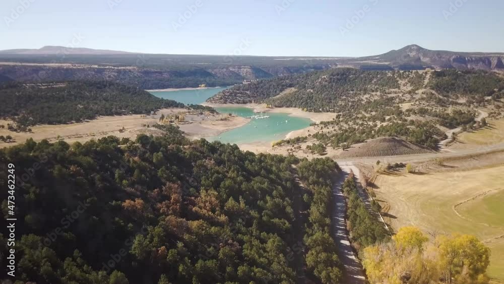 trucking shot showing beautiful aspen trees, a bright blue river with boat on it, rolling hills and a bright blue sky. trucking shot showing beautiful aspen trees, a bright blue river with boat on it, rolling hills and a bright blue sky.