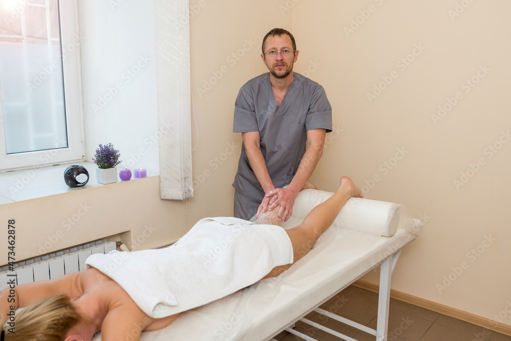 Fototapeta premium Beauty treatments in the spa. Masseur applying scrub on the legs of a girl. Scrubbing female feet in the spa.