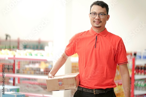 an employee of a supermarket wear uniform lifting inventory items