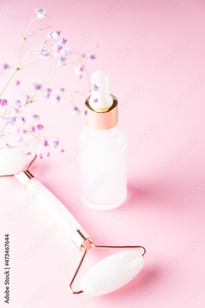 Skin care concept. Bottle of cometic product, serum or oil. Quartz roller for face massage. Cosmetics and tools on ponk background. Skin care concept. Bottle of cometic product, serum or oil. Quartz roller for face massage. Cosmetics and tools on ponk background.