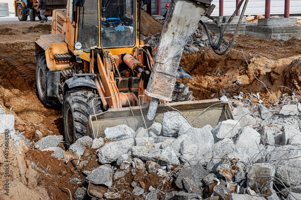 A powerful front loader on a construction site clears up the battle after dismantling reinforced concrete structures. Moving soil with construction equipment. Excavations. A powerful front loader on a construction site clears up the battle after dismantling reinforced concrete structures. Moving soil with construction equipment. Excavations.