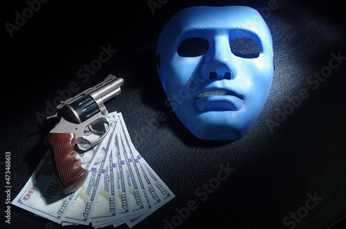Forensic science. Revolver, hundred dollar bills, bandit mask on a black background.