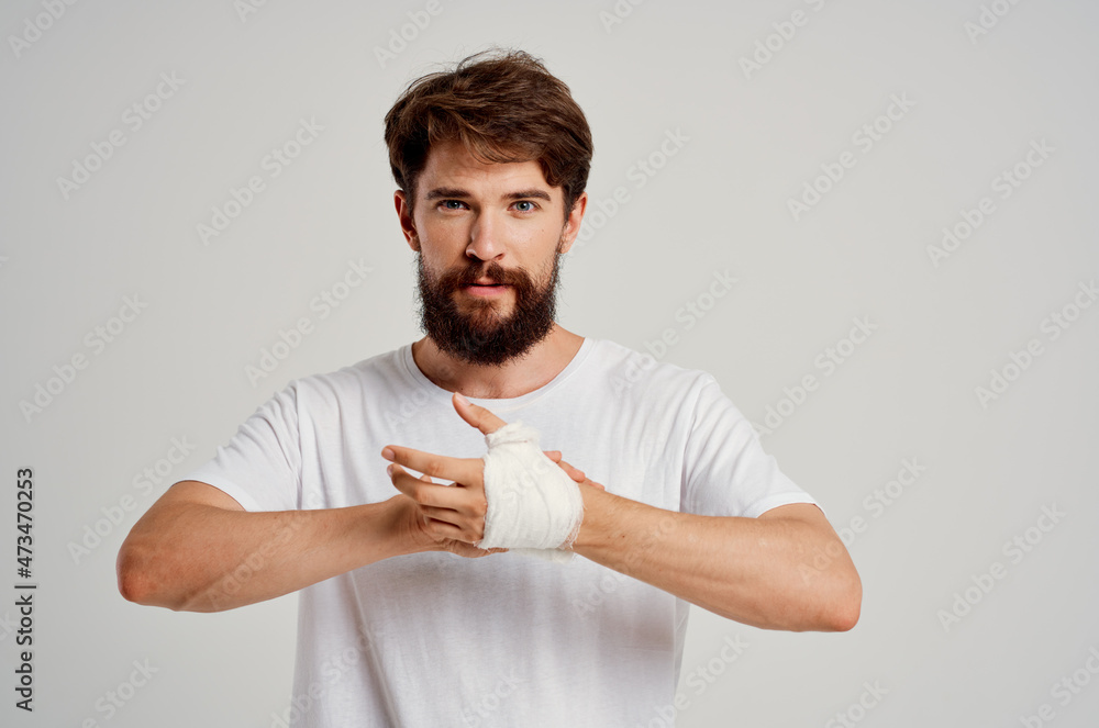 male patient in a white T-shirt with a bandaged hand posing isolated background male patient in a white T-shirt with a bandaged hand posing isolated background