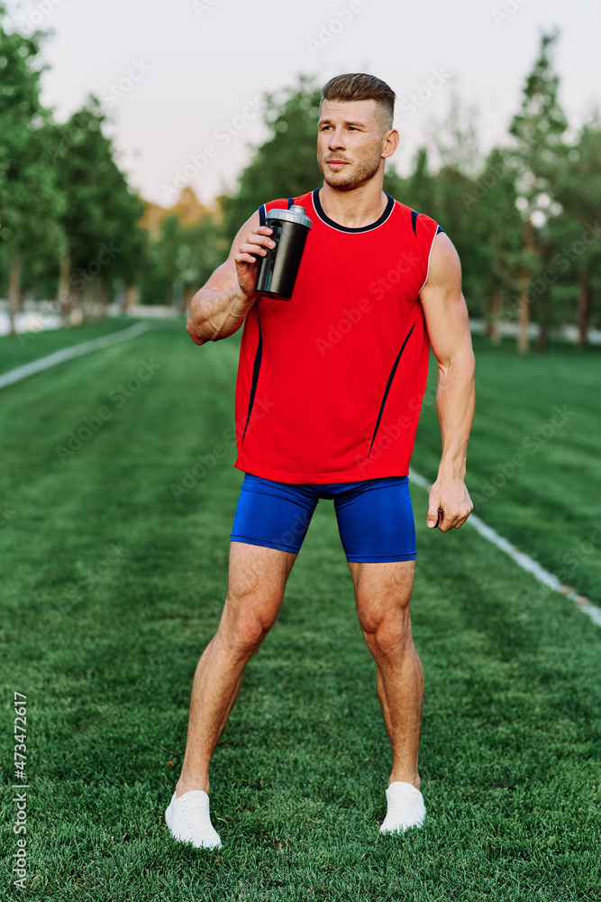 athletic man in red tank top posing outdoors fitness