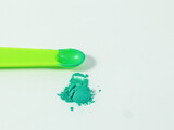 Green mica powder in measurement spoon on white isolated background