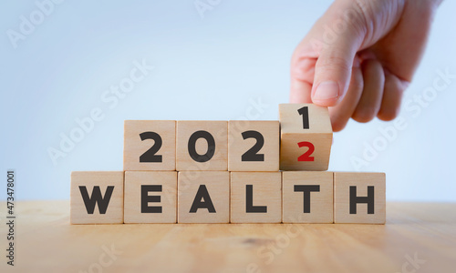 Fototapeta Naklejka Na Ścianę i Meble -  Wealth management concept in 2022..Financial management, money saving and investment for the future. Hand flips wooden cubes 2021 to 2022 with text 