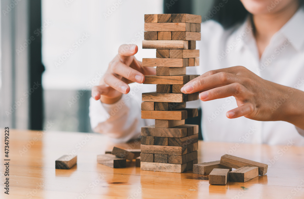 The business man's hand is planning a business strategy, the businessman plays the wooden block tower, Plans and strategies in the concept of a risky business The business man's hand is planning a business strategy, the businessman plays the wooden block tower, Plans and strategies in the concept of a risky business