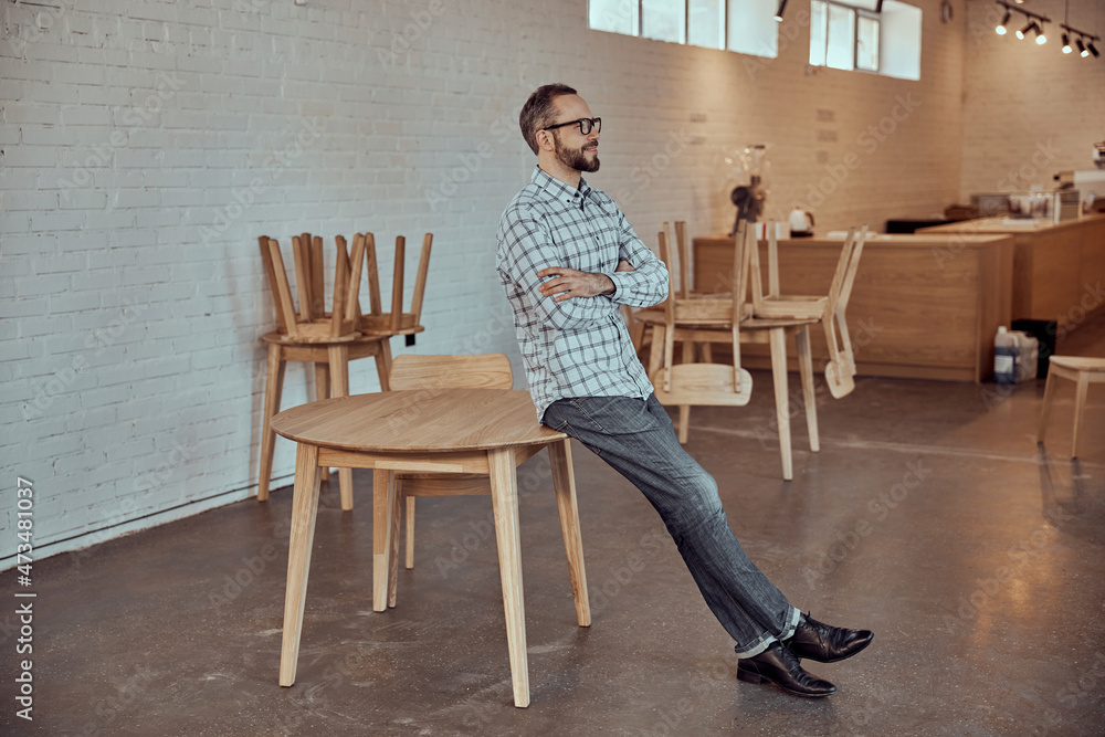 Joyful man sitting on the edge of table in cafe Joyful man sitting on the edge of table in cafe