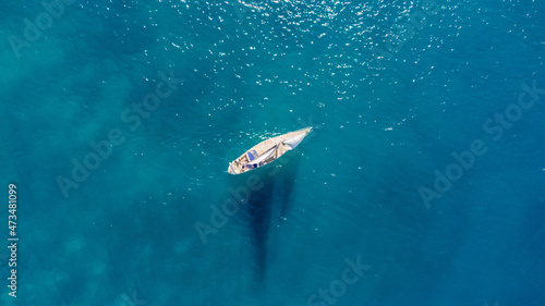 Drone aerial view of a sailing boat on a blue ocean sea waters. © astrosystem