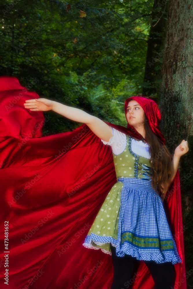 Little Red Riding Hood's cape flying out behind her while she is walking in the Black Forest of Germany on a fall day.