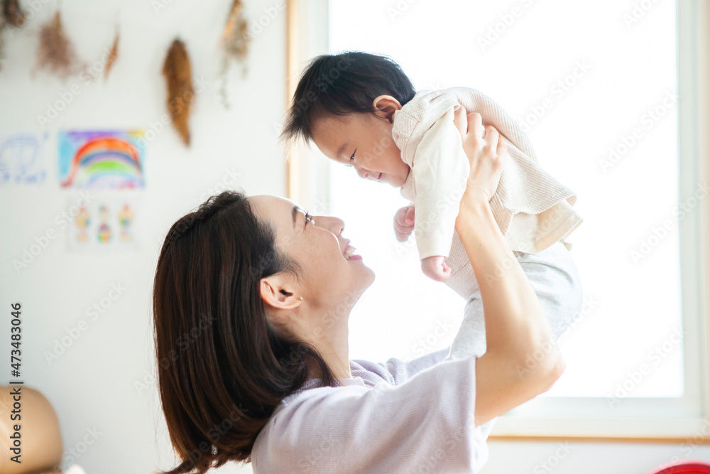 母親に抱き上げられて笑顔の赤ちゃん
