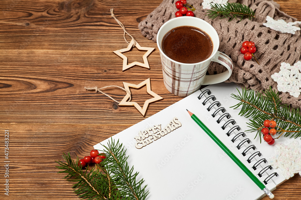 Christmas composition of open blank notepad, coffee cup, scarf and fir branches on wooden background Christmas composition of open blank notepad, coffee cup, scarf and fir branches on wooden background