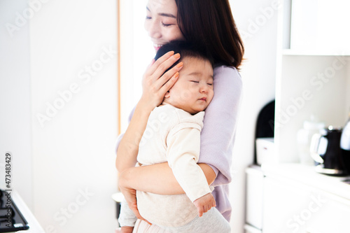 眠っている赤子を抱きしめる母親