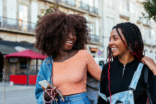 Cheerful ethnic women walking together on street