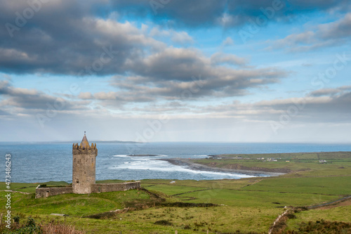 View on Doonagore castle, Doolin pier and Aran islands in the background. Beautiful cloudy sky. Popular tourist attraction in county Clare, Ireland. Fine example of old fortress.