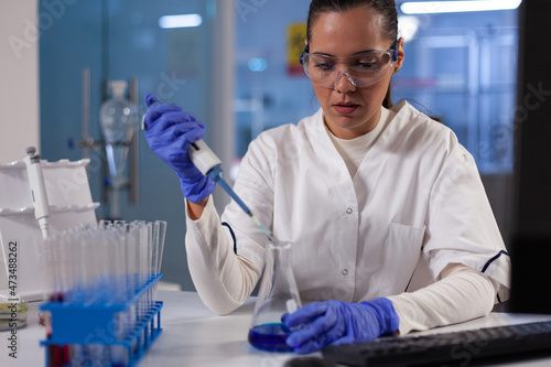 Photos Specialist researcher dropping medical blue solution in glassware using micropipette working at biochemistry experiment in hospital laboratory