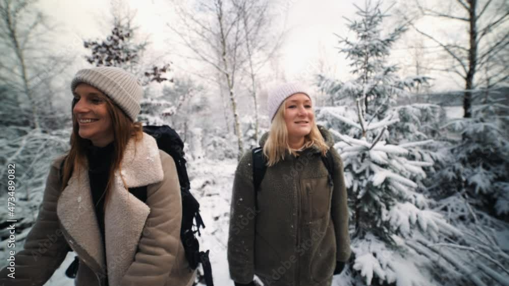 two jung hikers exploring a snowy forest landscape outside two jung hikers exploring a snowy forest landscape outside