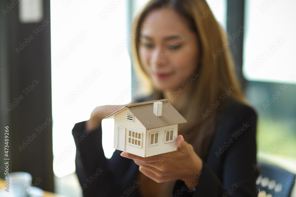 Close-up image of Female real estate agent holding house model Close-up image of Female real estate agent holding house model