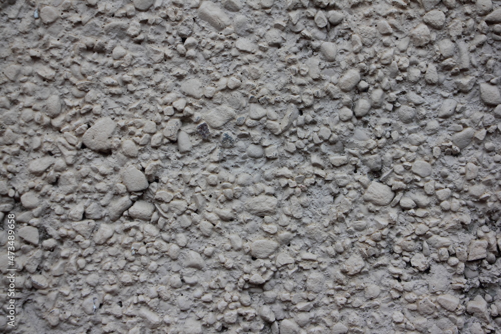 Rough grey dry concrete wall surface interspersed with crushed stone close up industrial background texture Rough grey dry concrete wall surface interspersed with crushed stone close up industrial background texture