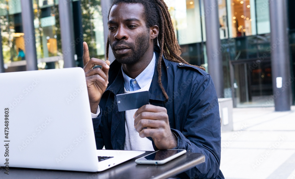 Concentrated man paying order in internet shop with credit card Concentrated man paying order in internet shop with credit card