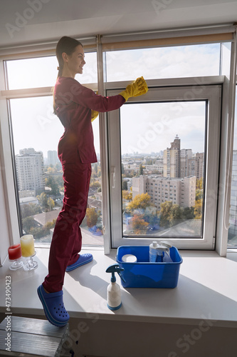 Принти на полотні Pleased cleaning lady wiping window-frame with microfiber cloth