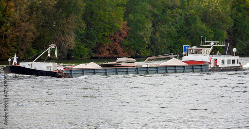 Valokuva Self-propelled cargo barge transports bulk construction materials along the river