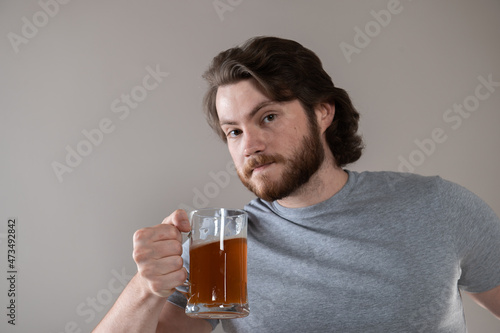 Bearded man with beer mug looking at camera over gray background