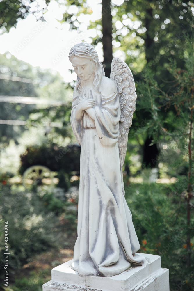 statue of guardian angel in a green forest