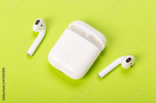 modern white wireless headphones with charging case on green background