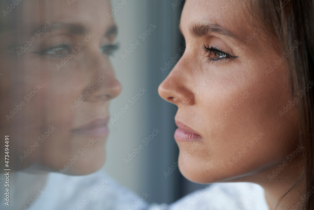 Sad woman looking through window at home Sad woman looking through window at home