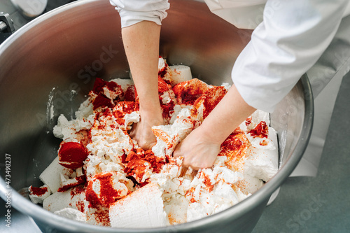 Skilled chef kneading cheese and ingredients in machinery at factory photo