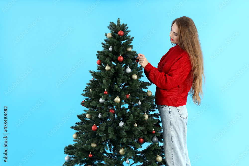 Attractive woman and Christmas tree on blue background