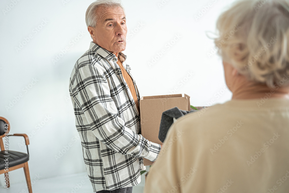Obraz premium Concentrated mature couple move into a new home and unpacking boxes of their belongings