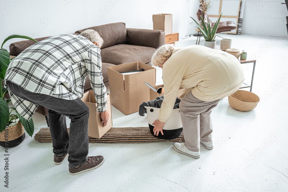 Senior couple unpacking boxes of their belongings while moving into a new home