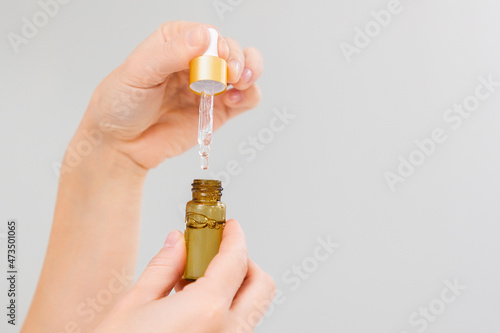 Close-up of elegant female hands holding a pipette with serum or cosmetic oil. Copy space. The concept of cosmetics and skin care