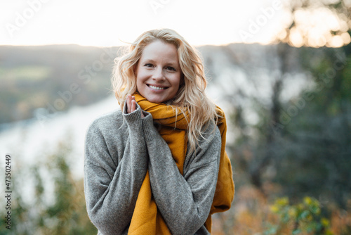 Blond woman in gray sweater smiling during sunset