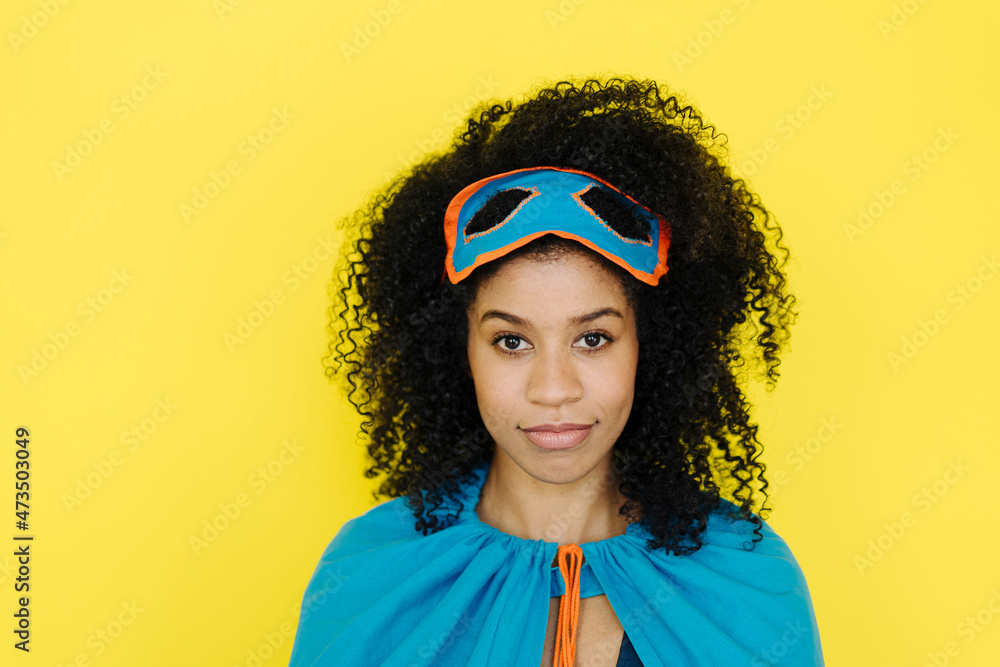 Afro woman wearing superhero costume standing on yellow background Afro woman wearing superhero costume standing on yellow background